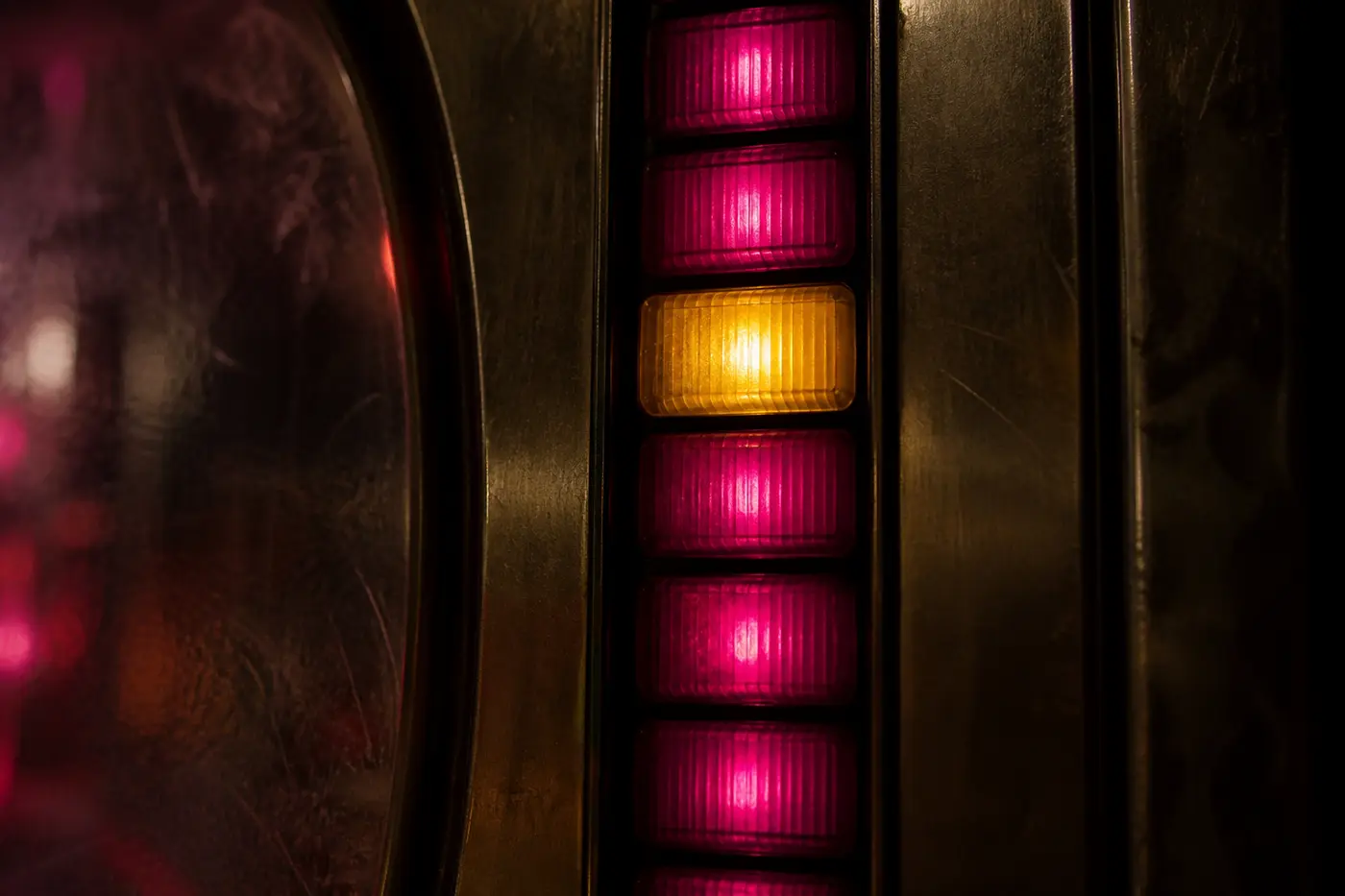 Nahaufnahme einer Lampensäule an der Front eines Geldspielgeräts: sieben übereinanderliegende Lampen leuchten magenta, eine davon warm gelb.